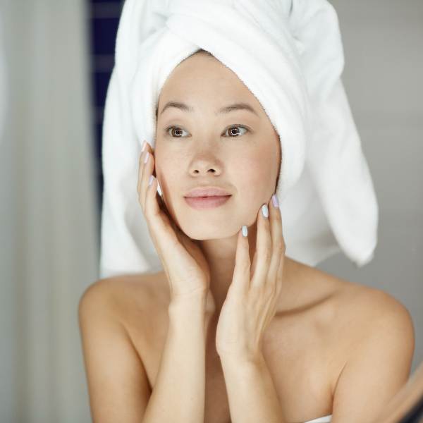Woman gently touching her face after cleansing as part of a hydrating fall skincare routine