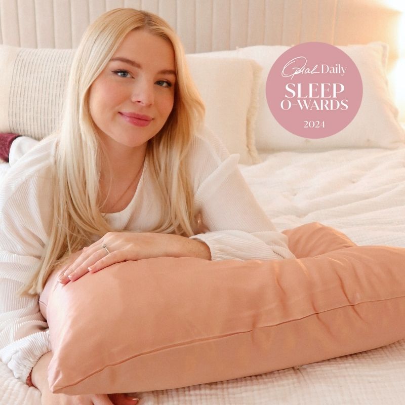 Woman relaxing with peach silk pillow, showing how silk helps skin and hair health naturally